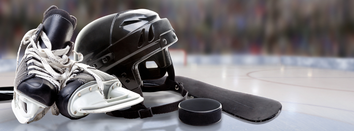 image of hockey black hockey skates, helmet, and puck on an ice rink